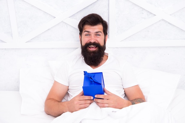 Fare il concetto di sorpresa Regalo per il coniuge Regalo carino e romantico Hipster barbuto preparare un bel regalo Regalo di San Valentino Diffondere l'amore Regalo per l'amante Uomo felice che si rilassa a letto Felicità