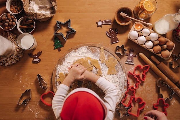 Fare il pan di zenzero a casa bambina che taglia i biscotti di pasta di pan di zenzero natale e capodanno