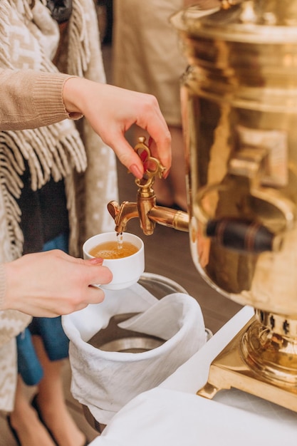 Fare il tè versando da un samovar tradizioni russe brillante caldaia che produce acqua bollente