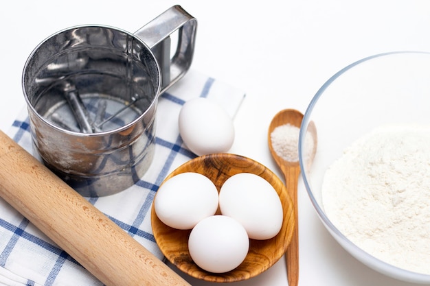 Fare impasti per pane o prodotti da forno fatti in casa. ingredienti in tavola: uova, farina, sale, mattarello