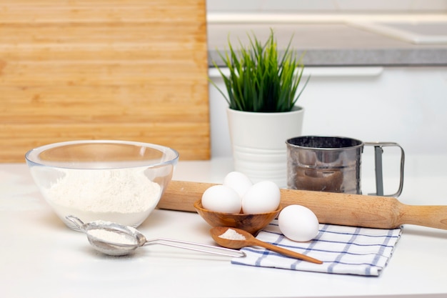 Fare impasti per pane o prodotti da forno fatti in casa. ingredienti sul tavolo. sullo sfondo di una luminosa cucina moderna
