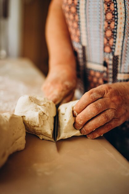 Fare l'impasto da mani senior femminili al forno. Concetto di cibo.