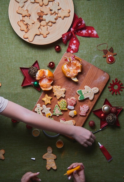 Fare l'uomo di pan di zenzero, pasta per biscotti. Il concetto di una festa in casa, una cena in famiglia. Concetto di tradizioni di Capodanno e processo di cottura. Biscotti sul tavolo verde in legno.