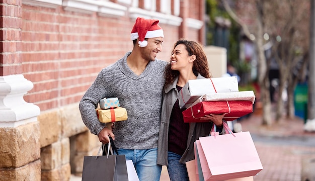 Fare lo shopping natalizio in anticipo Ritagliata immagine di una giovane coppia affettuosa che si gode lo shopping in città