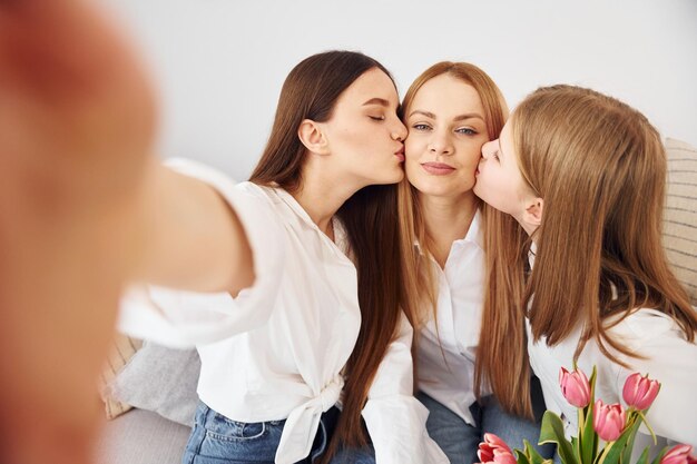 Fare selfie Giovane madre con le sue due figlie a casa durante il giorno