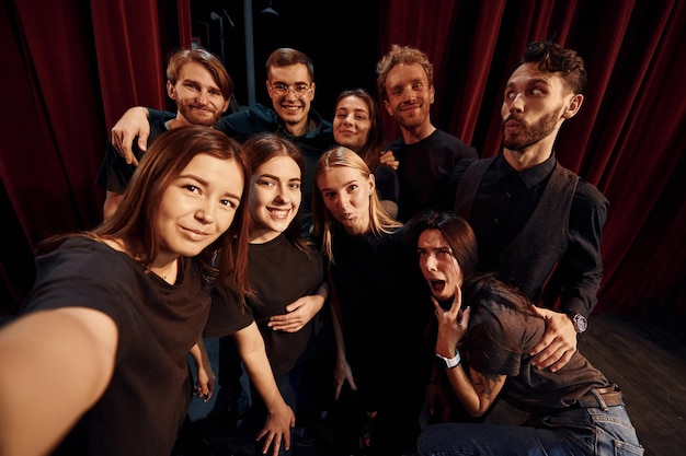 Fare selfie Gruppo di attori in abiti scuri durante le prove a teatro