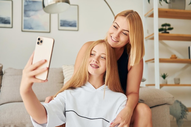 Fare selfie L'adolescente femminile con sua madre è a casa durante il giorno