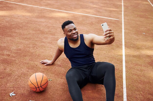 Fare selfie L'uomo afroamericano gioca a basket sul campo all'aperto