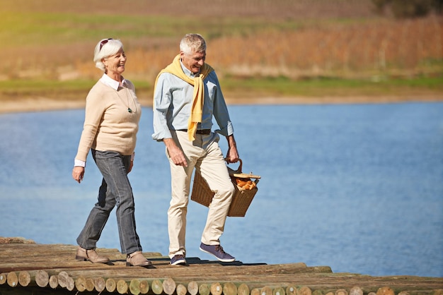 Fare una passeggiata sul lato spensierato della vita Inquadratura di una felice coppia senior che cammina lungo il molo di un lago