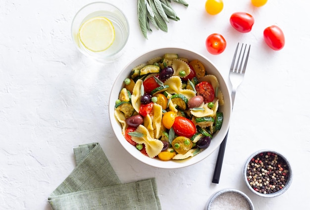 Farfalle di pasta con pomodori zucchine piselli Olive Kalamata e salvia Alimentazione sana Cibo vegetariano