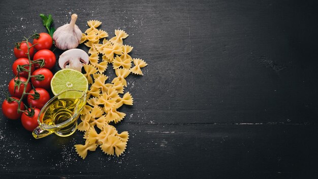 Farfalle di pasta secca con verdure su fondo di legno Vista dall'alto Spazio di copia