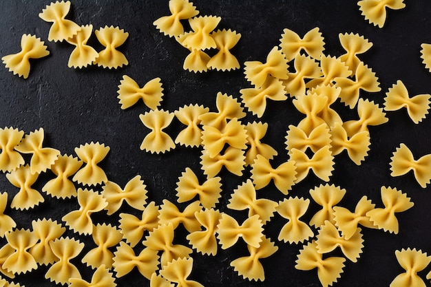 Farfalle pasta cruda sulla tavola di cemento nero. Concetto di cucina. Vista dall'alto con copia spazio.