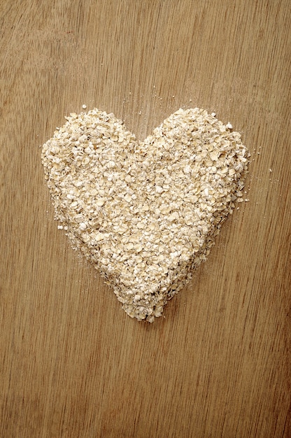 Farina d&#39;avena a forma di cuore su fondo di legno. Buono per il concetto di cibo sano