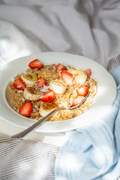 Farina d'avena con banana, fragole e burro di arachidi nel piatto bianco nel letto backgrond.