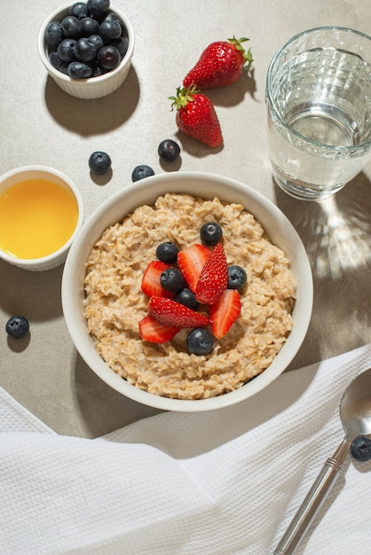 Farina d'avena con frutti di bosco e miele su un tavolo grigio