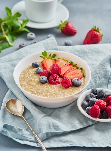 Farina d&#39;avena con mirtillo, fragola, lampone su sfondo blu scuro.