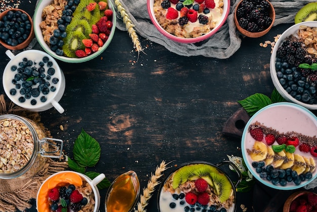 Farina d'avena con yogurt, frutta e bacche in piatti Colazione su uno sfondo di legno nero Vista dall'alto Spazio libero per il testo