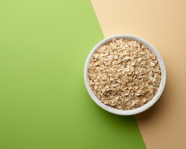 Farina d'avena cruda in una ciotola di legno bianca