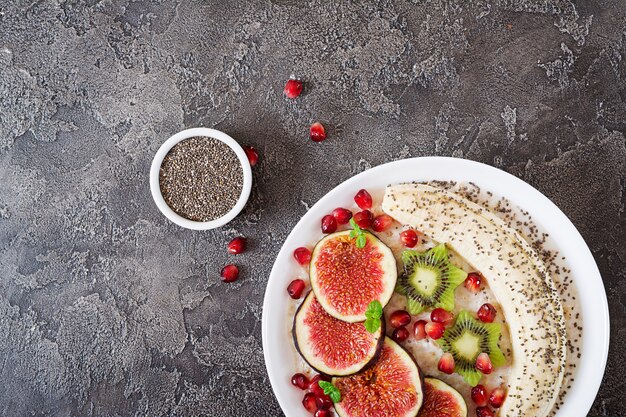 Farina d'avena deliziosa e sana con semi di fichi, kiwi, melograno, banana e chia. Colazione salutare. Nutrizione appropriata. Disteso. Vista dall'alto.