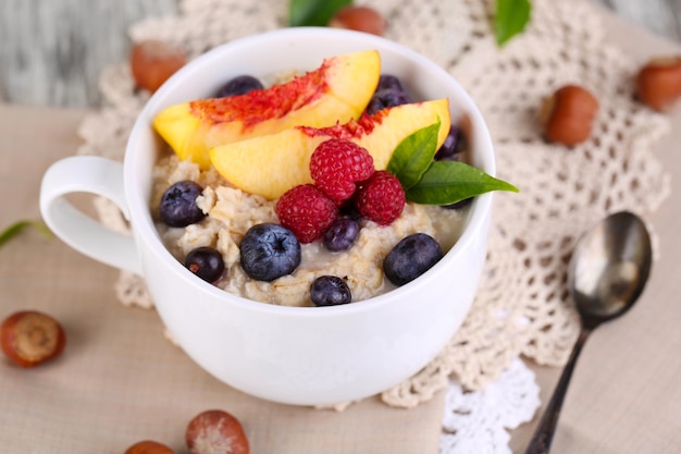 Farina d'avena in tazza con frutti di bosco sui tovaglioli sulla tavola di legno