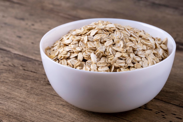 Foto farina d'avena laminata a secco in una ciotola su fondo di legno