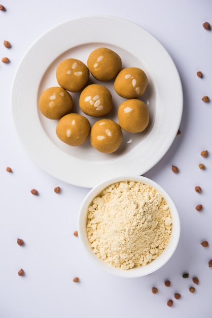 Farina di ceci o polvere di Besan in una ciotola di ceramica o legno insieme a Laddu dolce o laddoo