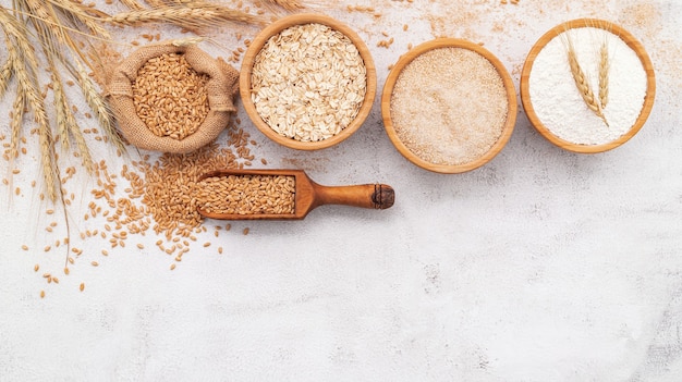 farina di frumento in ciotola di legno allestita su sfondo di cemento bianco.