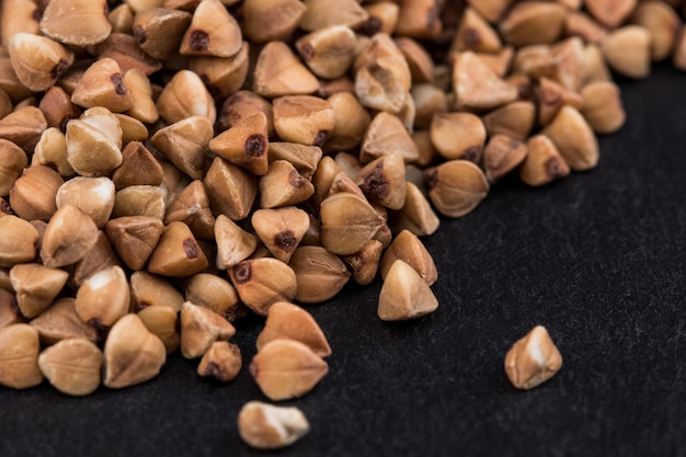 Farina di grano saraceno su sfondo nero. Mucchio di semole di grano saraceno Close up