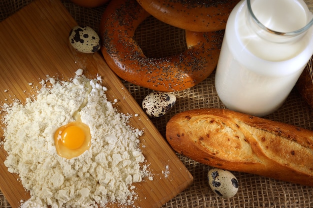 Farina e uovo su una tavola in una panetteria, accanto a una baguette pronta e una bottiglia di latte