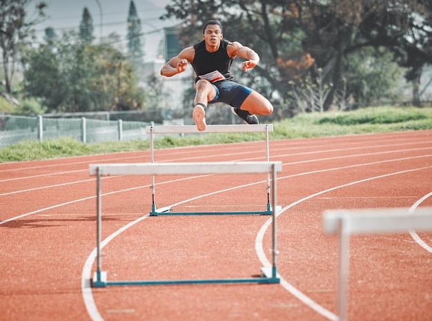 Farlo sembrare facile. Colpo integrale di un bel giovane atleta maschio che pratica gli ostacoli su una pista all'aperto.