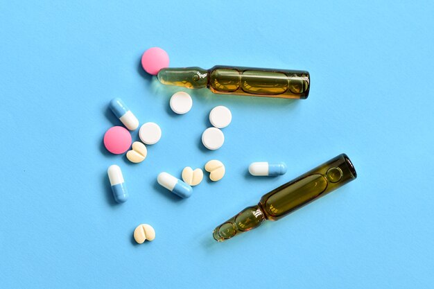 Farmaci assortiti e fiala su sfondo blu