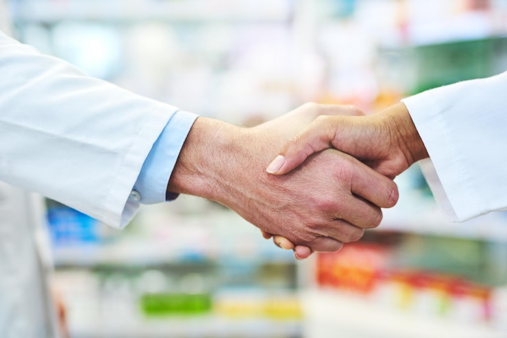Foto farmacia in primo piano e persone con stretta di mano cooperazione e lavoro di squadra per l'assistenza sanitaria stretta di mano dipendenti e colleghi di lavoro in farmacia collaborazione e partnership con supporto e grazie