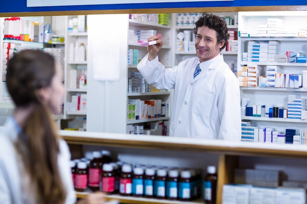 Farmacista che sta al contatore e che mostra la scatola della medicina