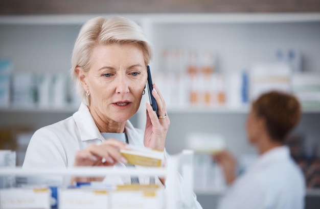 Farmacista e donna in farmacia al telefono con medicine o pillole in negozio per la telemedicina Smartphone sanitario e medico senior in consultazione con il contatto per la prescrizione di farmaci