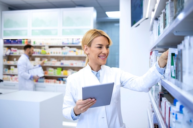 Farmacista femminile che lavora in farmacia o in farmacia su computer tablet.