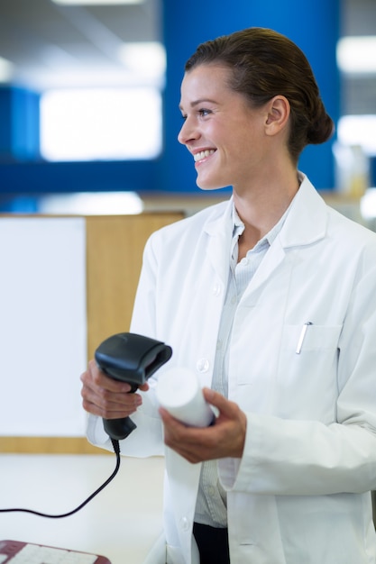 Farmacista sorridente che usando l'analizzatore del codice a barre sulla bottiglia della medicina