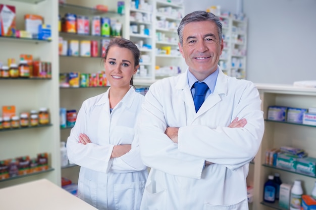 Farmacista sorridente e il suo tirocinante a braccia incrociate