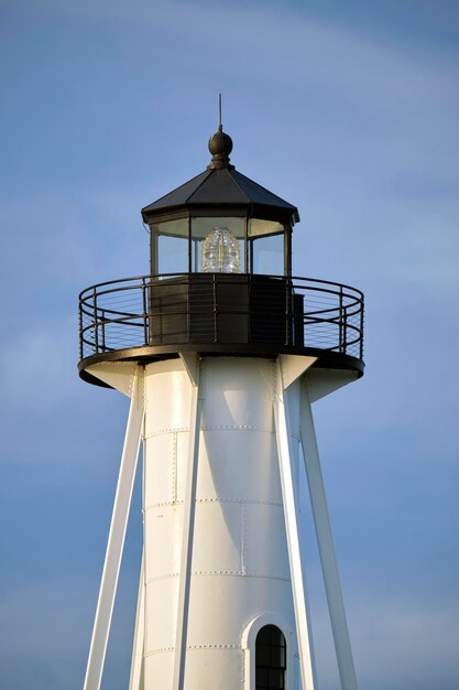 Faro alto bianco sulla riva del mare contro il cielo blu per la navigazione di navi commerciali