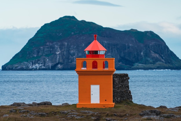 Faro arancione con un enorme isolotto sullo sfondo