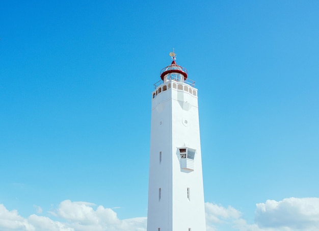 faro bianco su sfondo blu cielo vicino al mare