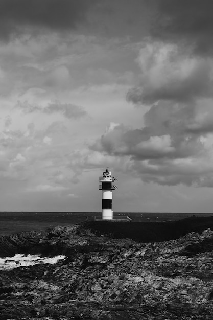 Faro in bianco e nero con enormi nuvole