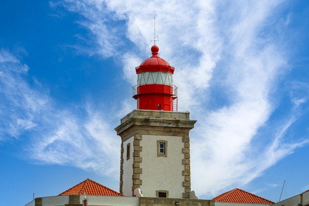 Faro in cima a una scogliera di roccia e cielo blu con nuvole. Lisbona Portogallo.