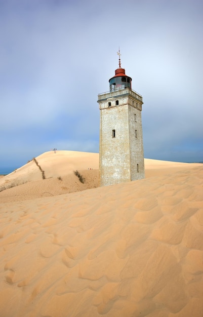 Faro su una duna di sabbia in riva al mare contro un cielo blu Misteriosa vecchia torre da sola nel deserto Faro deserto isolato su sabbia beige Scena della natura pacifica e tranquilla nello Jutland Danimarca