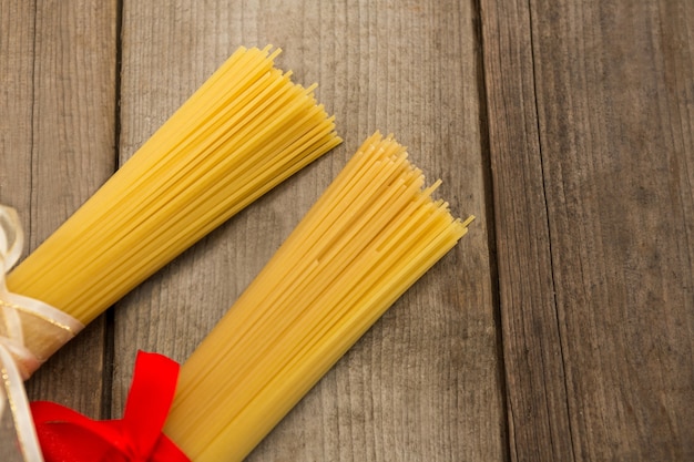 Fasci di spaghetti crudi legati con nastri su una superficie di legno