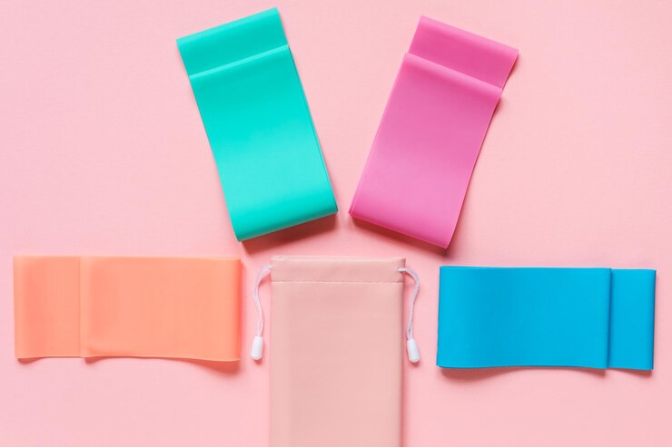 Fascia elastica di resistenza e custodia sullo sfondo rosa, attrezzature sportive o per il fitness.