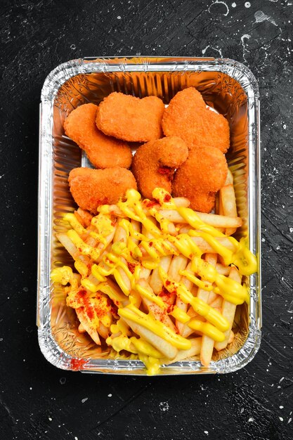 Fast food patatine fritte e nuggets di pollo in un piatto usa e getta su una tavola di legno