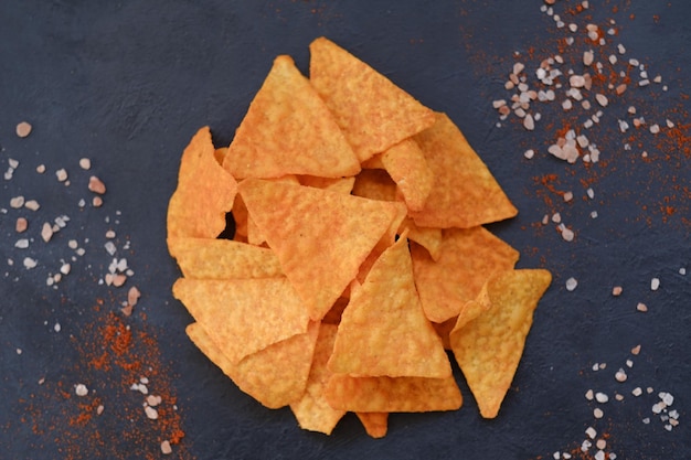 Fast food spazzatura e cibo malsano tortilla chips nacho patatine triangolari croccanti su sfondo scuro