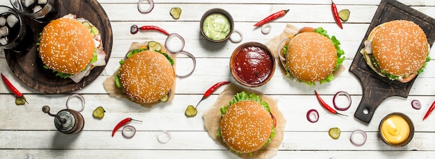 Fast food. Vari hamburger con carne di manzo e verdure fresche. Su un tavolo di legno bianco.