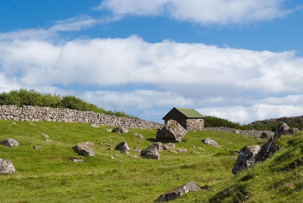 Fattoria a Torshavn, Danimarca. Vecchia casa di pietra nel cortile di fattoria sul cielo blu nuvoloso. Tipica architettura rurale. Natura e ambiente. Bella vista del paesaggio. Vacanze estive in paese.