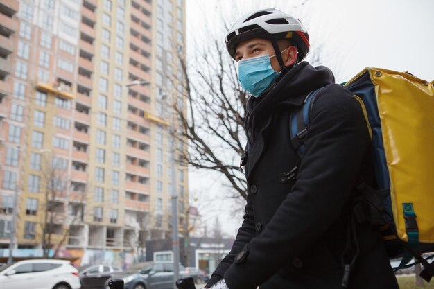 Fattorino che indossa una maschera medica, passeggiando per la città in autunno o in inverno